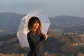 Smiling woman with white umbrella at sunset