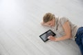 Smiling woman on wooden floor using tablet Royalty Free Stock Photo