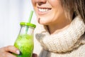 Smiling woman in woollen sweater drinking green homemade detox smoothie or juice. Healthy clean eating Royalty Free Stock Photo