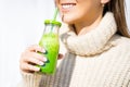 Smiling woman in woollen sweater drinking green homemade detox smoothie or juice. Healthy eating Royalty Free Stock Photo