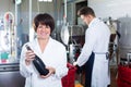 Woman worker displaying wine bottle Royalty Free Stock Photo