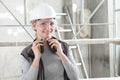 Smiling woman worker portrait wearing helmet, safety glasses and hearing protection headphones, scaffolding interior construction Royalty Free Stock Photo