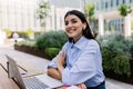 Smiling woman working online with laptop sitting outside of his office building Royalty Free Stock Photo