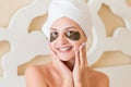 Smiling woman wrapped in towel after bath and with black patches under eyes is posing on the bed. Beauty treatment concept Royalty Free Stock Photo