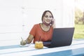 Smiling woman 40 years old wearing open protective face mask using laptop and cell phone during the end of coronavirus outbreak. Royalty Free Stock Photo