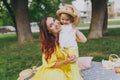 Smiling woman in yellow dress play in park amuse and hug, embrace with little child baby girl hold soap bubble blower Royalty Free Stock Photo