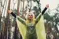 Smiling woman in yellow raincoat walking in autumn forest enjoying rainy weather outdoors. Female tourist discover park Royalty Free Stock Photo