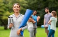 Smiling woman with yoga mat and bottle at park Royalty Free Stock Photo