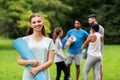 Smiling woman with yoga mat over group of people Royalty Free Stock Photo