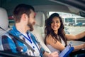 Happy woman and drive instructor looking each other while sitting in the car during driving lesson. Driving test, driver Royalty Free Stock Photo