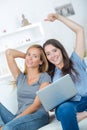 Smiling women looking financial documents with laptop in home