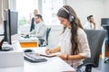 Smiling woman operator agent with headset taking notes while talking with client in call center. Royalty Free Stock Photo