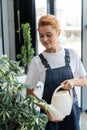 smiling woman in overalls watering green Royalty Free Stock Photo