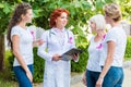 smiling women with pink ribbons looking at doctor with clipboard breast cancer awareness