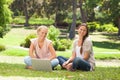 Smiling women sitting in the park with a laptop Royalty Free Stock Photo