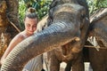 Smiling woman stroking the trunk of a large Asian elephant