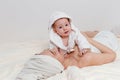 smiling woman with a towel on her head and a baby girl in a Bathrobe lie on the bed after bathing Royalty Free Stock Photo