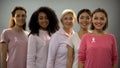 Smiling women wearing pink clothes and ribbons, breast cancer awareness sign