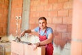 Smiling worker building brick walls with cement, mortar and putty knife. Mason using mortar for building walls Royalty Free Stock Photo