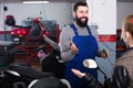 Smiling worker help to woman to repair motorcycle Royalty Free Stock Photo