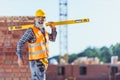 Smiling worker in reflective vest and hardhat walking with spirit level across Royalty Free Stock Photo