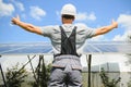 Smiling worker with solar station, raising his hands, showing thumbs up on a background of photovoltaic panels near the Royalty Free Stock Photo