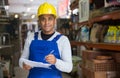 Smiling worker taking notes during inventory in hardware store