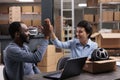 Smiling workers doing high five after putting helmet order for client in cardboard box Royalty Free Stock Photo