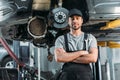 smiling workman posing with crossed arms in auto