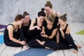 Smiling yogi girl exercising, having a break at class, group of friends watching on the phone Royalty Free Stock Photo