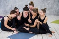 Smiling yogi girl exercising, having a break at class, group of friends watching on the phone Royalty Free Stock Photo