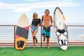 Smiling young active couple surfers relaxing on the beach after sport with Surfboard. Healthy Lifestyle. Extreme Water