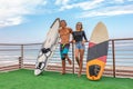 Smiling young active couple surfers relaxing on the beach after sport with Surfboard. Healthy Lifestyle. Extreme Water