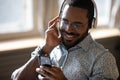 Smiling african man wearing headphones listen mobile music on smartphone