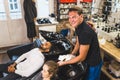 Smiling young adult male hairdresser looking at camera while washing the hair of his female client. Washing station Royalty Free Stock Photo