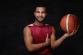 Smiling young African-American basketball player in sportswear isolated over dark background. Royalty Free Stock Photo