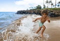 Smiling young African American boy running and playing at the beach while on a family vacation Royalty Free Stock Photo