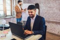 Young African American businessman working online with a laptop while sitting at his desk in a modern office Royalty Free Stock Photo