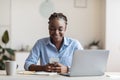 Smiling young african american businesswoman using smartphone at workplace in office Royalty Free Stock Photo