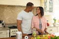 Smiling young african american couple romancing while cooking food together in kitchen at home Royalty Free Stock Photo