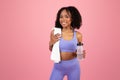 Smiling young african american curly lady in sportswear with towel and bottle of water, enjoy sport