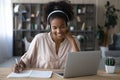 Smiling biracial woman in headphones work on laptop