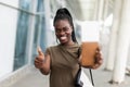 Smiling young african girl hold passport boarding pass tickets showing thumb up in airport terminal Royalty Free Stock Photo