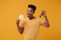 Smiling young african american guy in casual t-shirt posing isolated on yellow orange background, studio portrait