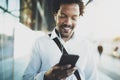 Smiling young African American man in headphone walking at sunny city and enjoying to listen to music on his mobile Royalty Free Stock Photo