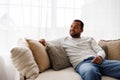 Smiling young african american man relaxing on couch with pillows at home, copy space Royalty Free Stock Photo