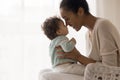 Smiling young african american mommy touching noses with cute kid.