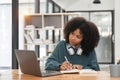 Smiling young african american teen girl wear headphones video calling on laptop. Happy woman student looking at Royalty Free Stock Photo