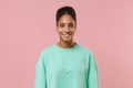 Smiling young african american woman girl in green sweatshirt posing isolated on pastel pink background studio portrait Royalty Free Stock Photo