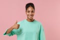 Smiling young african american woman girl in green sweatshirt posing isolated on pastel pink background studio portrait Royalty Free Stock Photo